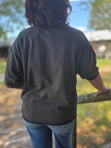 Woman wearing a gray terry crew neck shirt with half sleeves, styled casually with blue jeans and white slip-on sneakers.