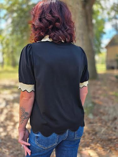 Black puff sleeve blouse with cream contrast scalloped collar and sleeve trim, featuring a V-neckline.