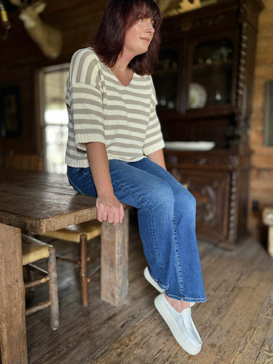 Woman wearing dark wash high-rise crop straight jeans with a striped knit top and casual slip-on shoes.