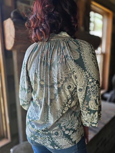Person wearing a patterned green blouse in an indoor setting