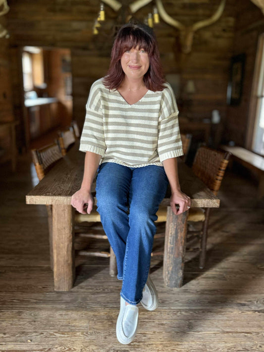 Woman wearing dark wash high-rise crop straight jeans with a striped knit top and casual slip-on shoes.