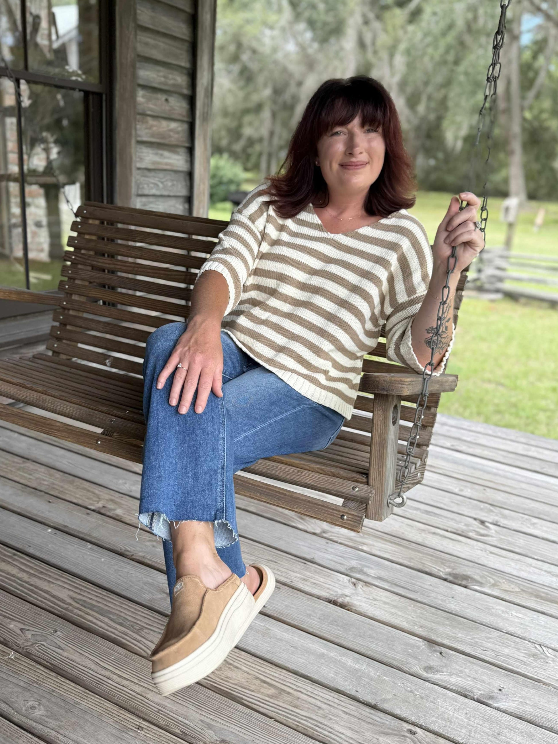 Woman wearing medium wash high rise crop straight jeans with raw hem, styled with a striped knit top and slip-on shoes.