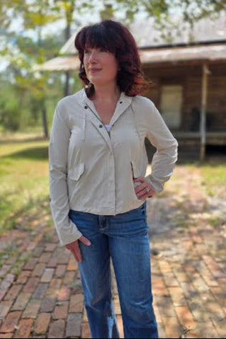 Woman wearing a cream snap button zip-up hoodie with front pockets, styled with denim jeans outdoors.
